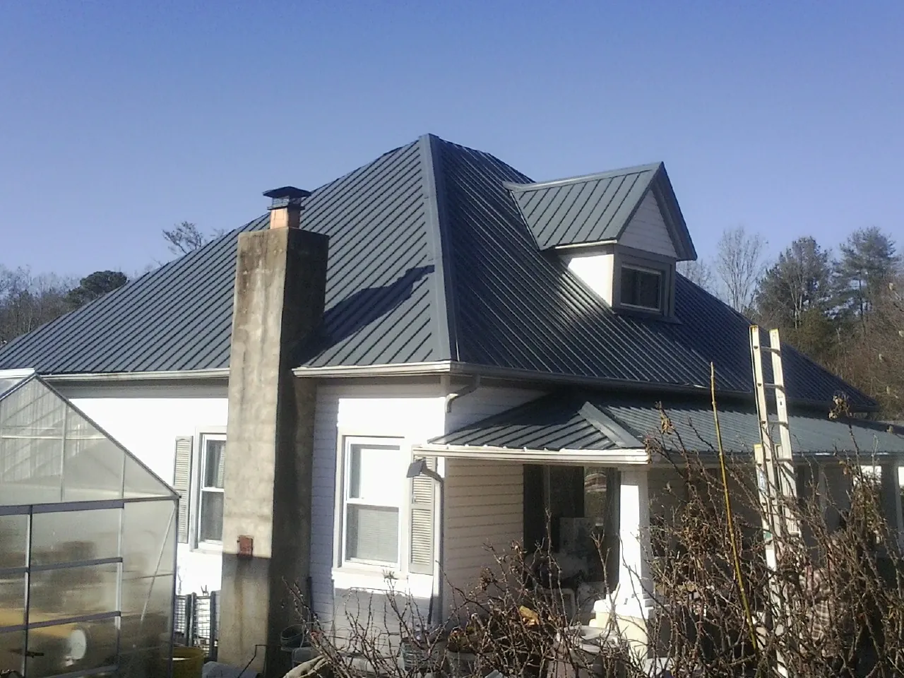 Dark blue standing seam metal roof on a white farmhouse with dormer — Slate & Tile Roof Repair by Roofing Brothers in Griffin