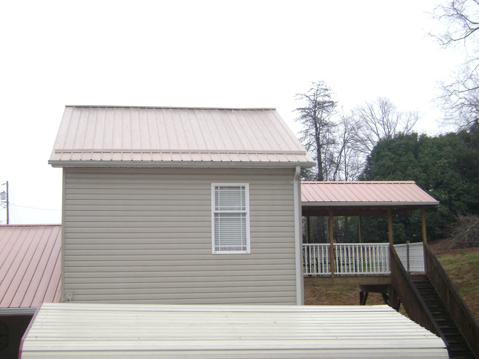 Tan metal roofs on a two story addition and attached porch, from a Roof Replacement job in Griffin