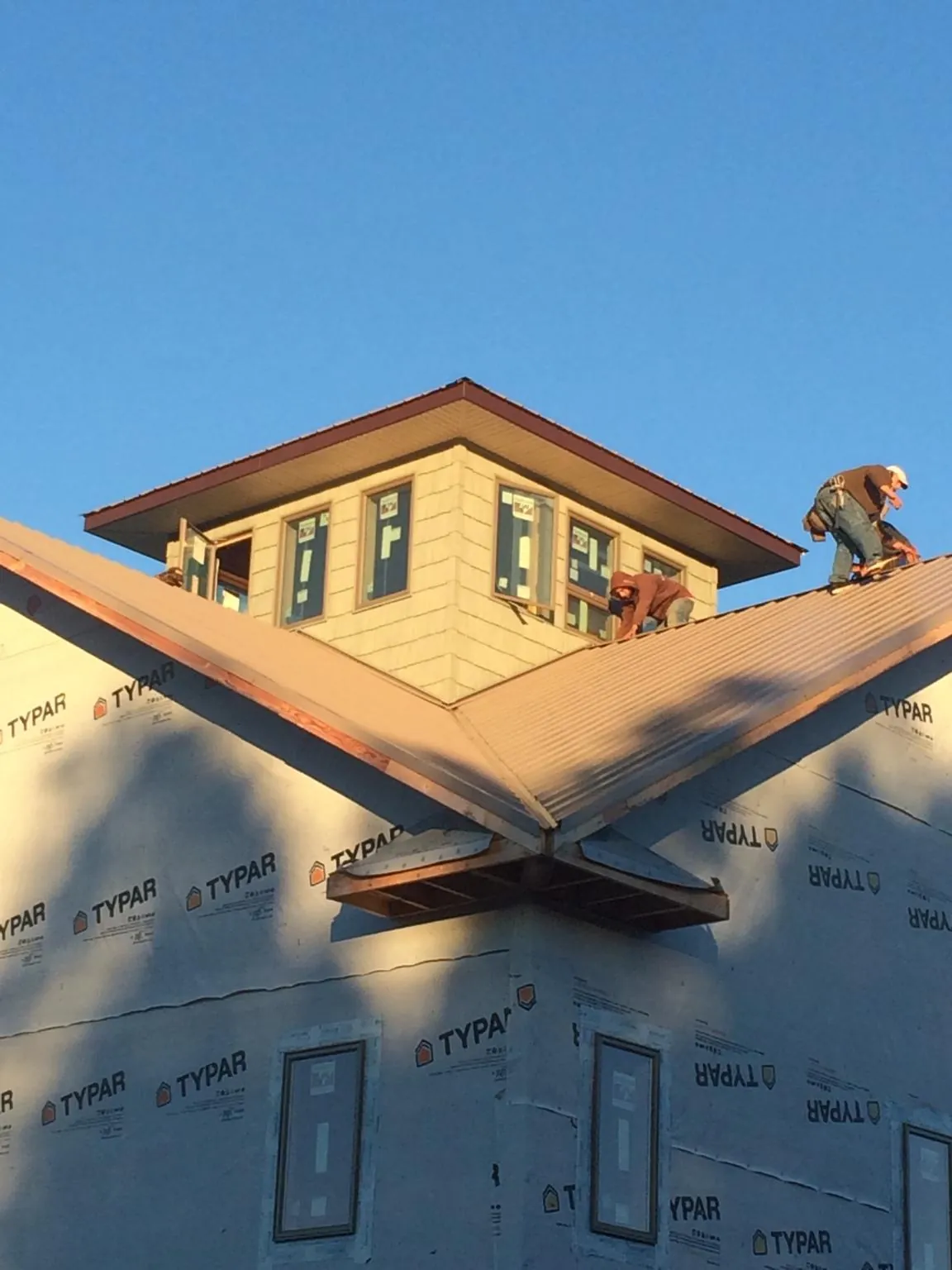 Roofers working around a rooftop cupola on a new metal roof at sunset — Roof Waterproofing in Griffin by Roofing Brothers
